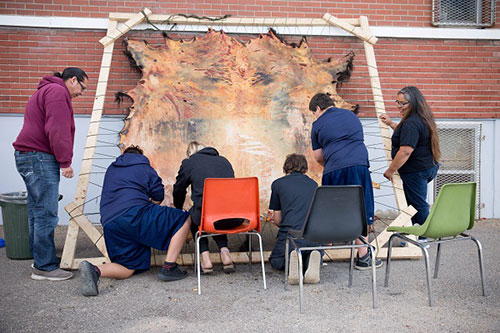 Students scraping buffalo hide