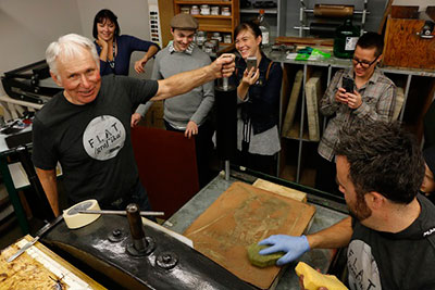 Chrissy Poitras and Kyle Topping watch Otis Tamasauskas during his stone lithography demo at the University of Regina Print Media Studio as part of Flatgrafika print symposium