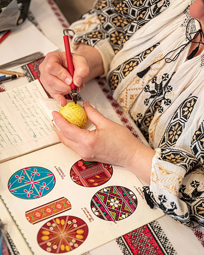 A woman decorating a Ukrainian Easter egg