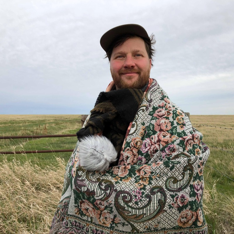 Jeff Morton - Man standing in open field in blanket