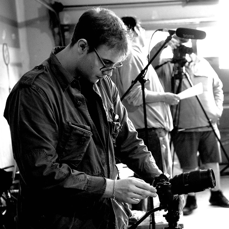 Liam Scramstad - Black and white photo of man looking at a camera