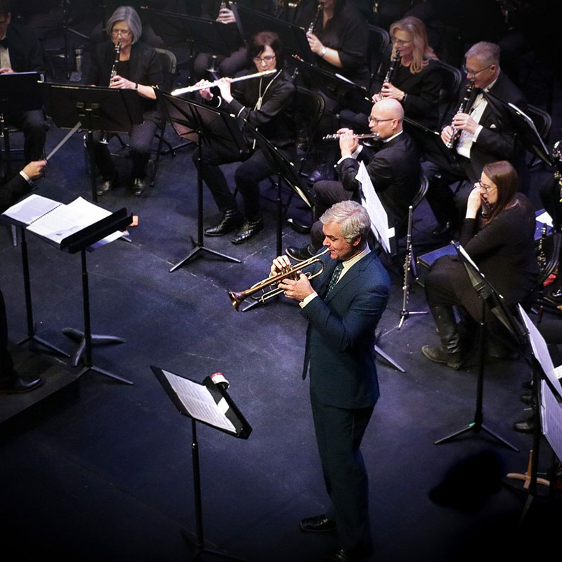 Dean McNeill - Man on a stage wearing a suit and blowing an instrument