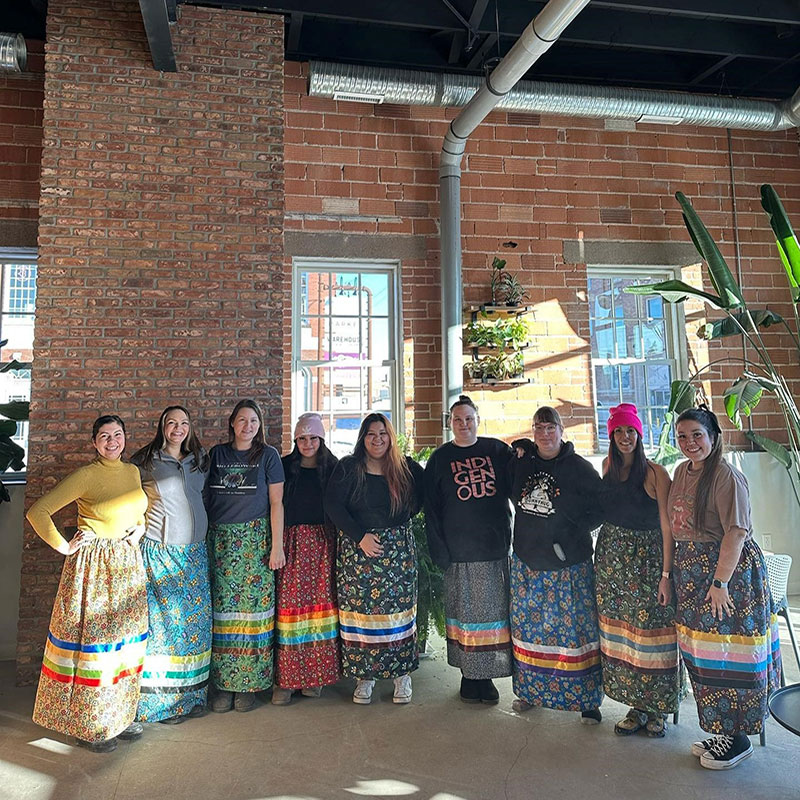 The Comeback Society - Nine women in ribbon skirts posing for a picture