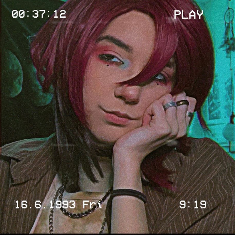 Luka Kelly - Picture of young person with red hair and hand on their cheek