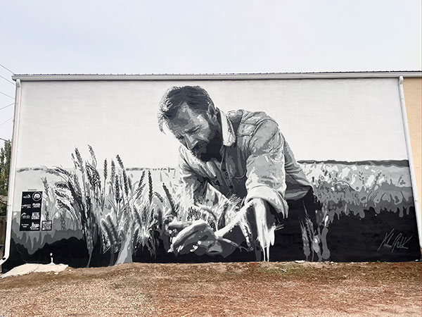 Shaunavon, Saskatchewan mural by Andrew Robertson, showing a farmer bending over tending a crop in a field