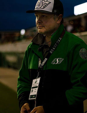 R. Corey Taylor, SK Arts Arts of Celebration 2025. Corey Taylor, band player, man in a a green and white Rider apparrel (hat green jacket with field pass hanging around his neck).